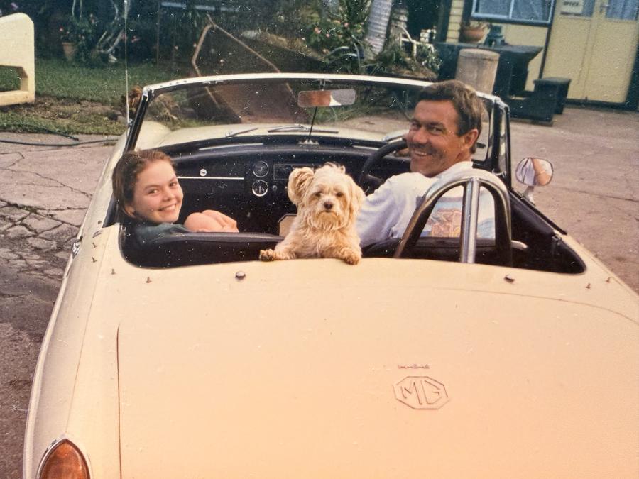Young Amy and her dad in his cream MG convertible, with Blossom perched on the back